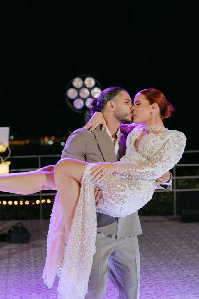 Andreas & Ioanna, wedding in Patras: the groom lifts the bride in his arms, at night