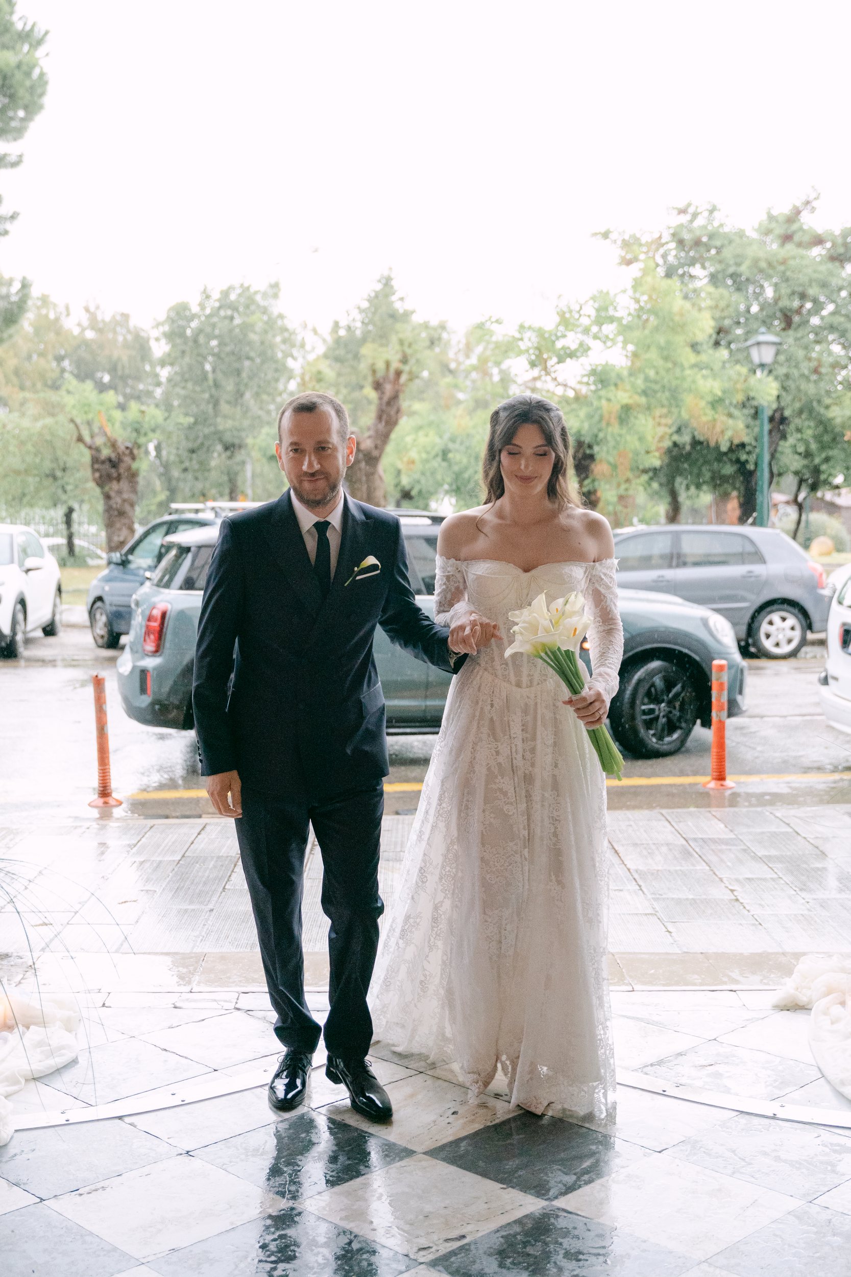 The bride and her father walking to the church across the wet churchyard