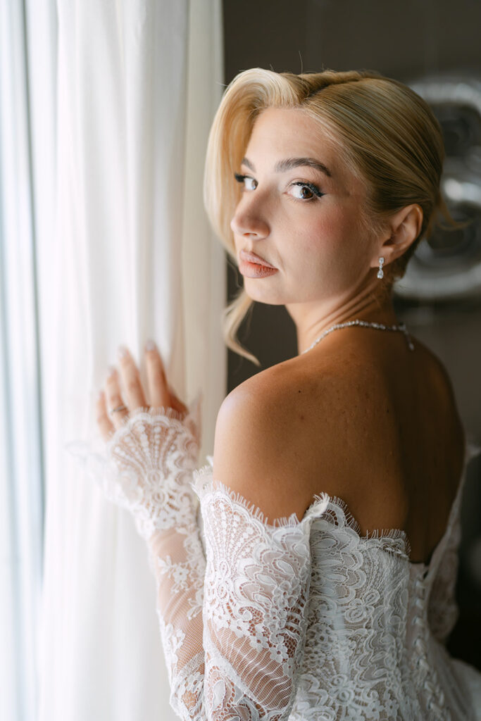 Konstantinos & Katerina, wedding in Athens: the bride at the window curtain