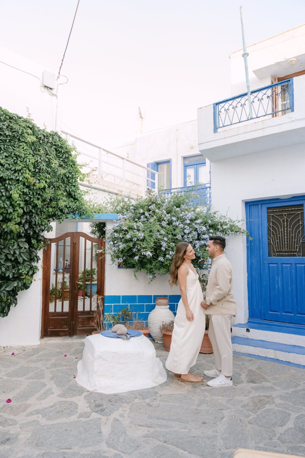 Couple by a blue door and flowers in Plaka